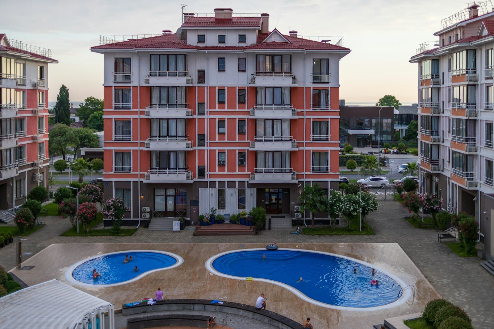 A residential building with balconies surrounding a community swimming pool and landscaped courtyard