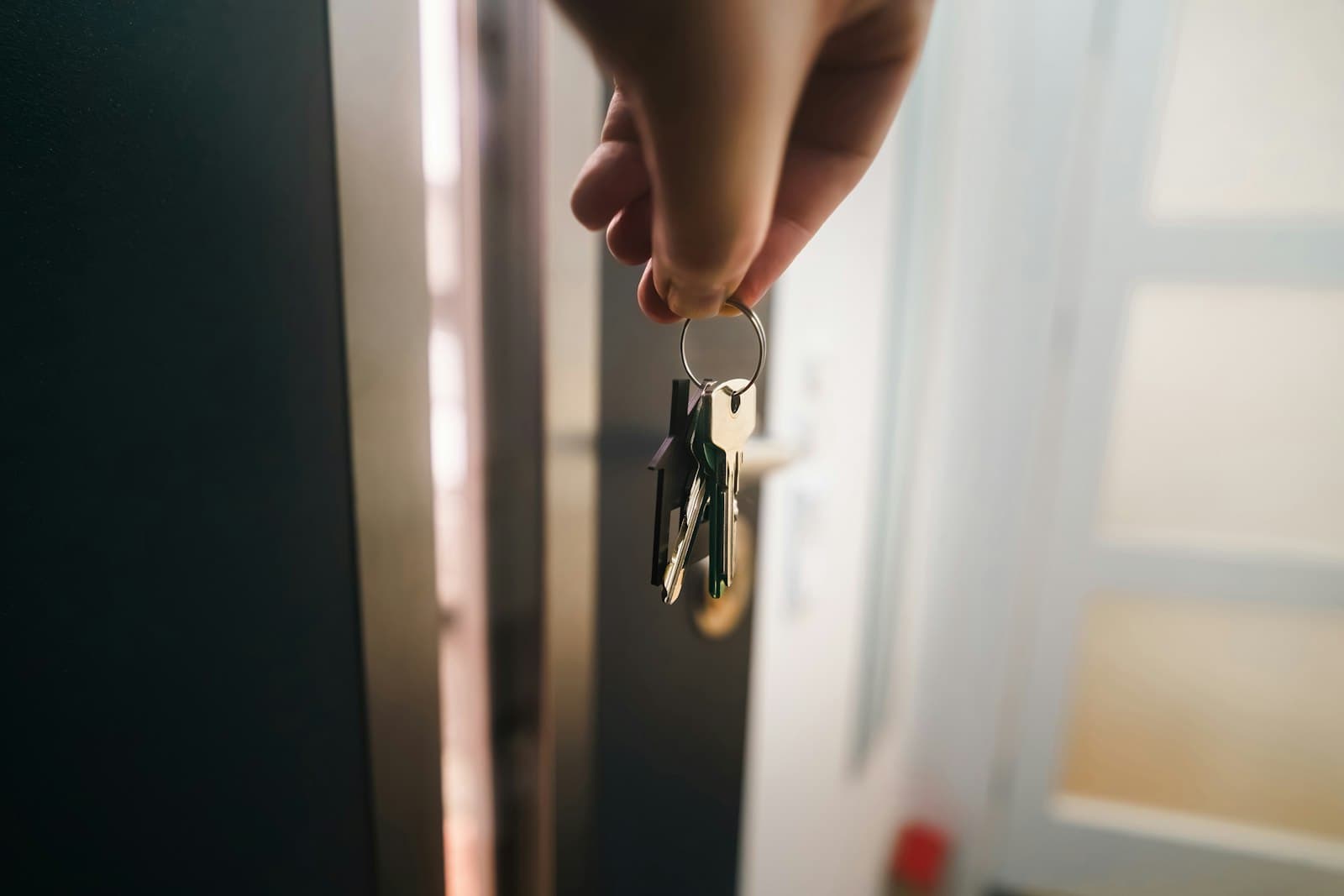 A hand holding a set of house keys in an open doorway